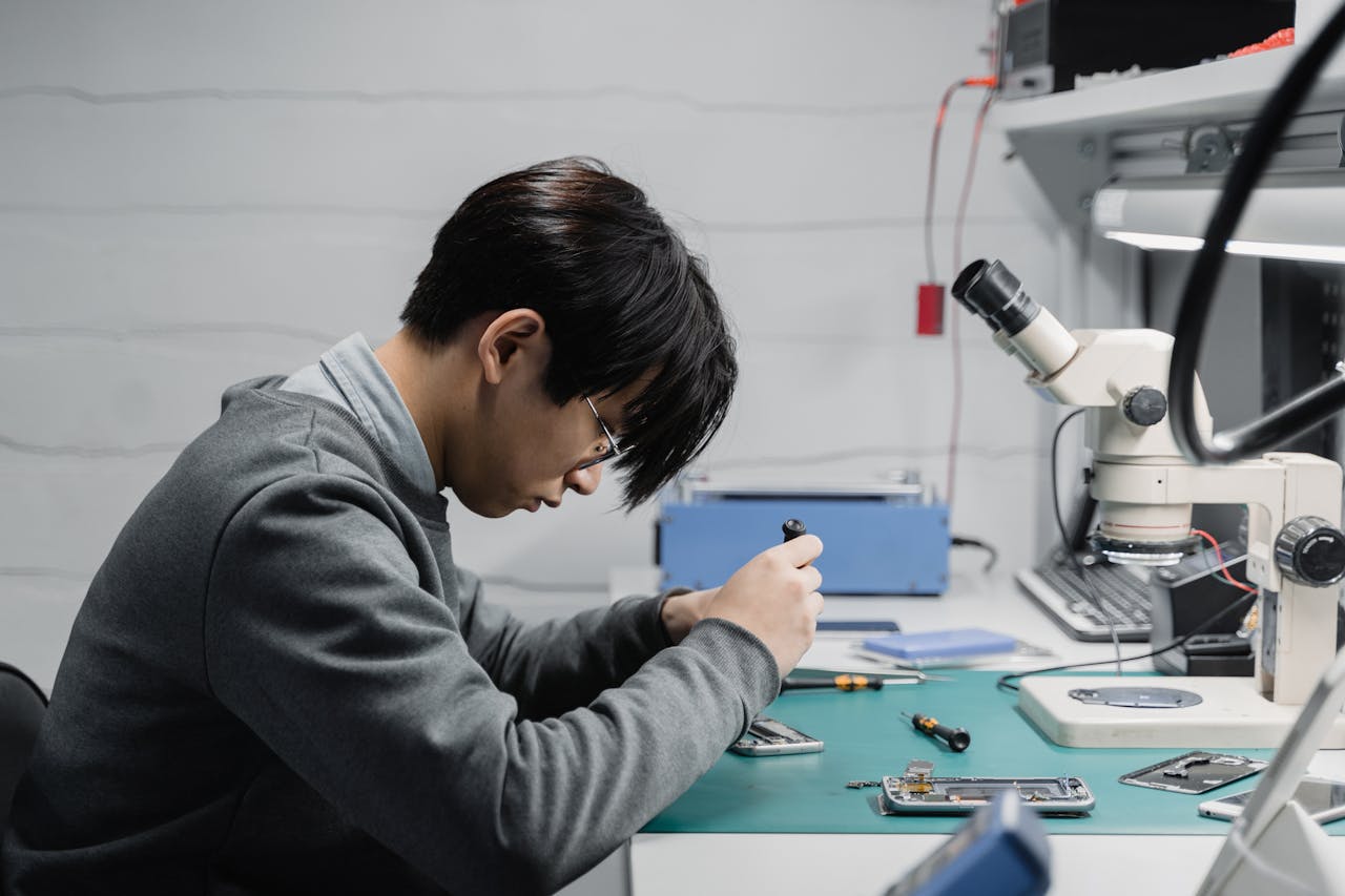 journey Professional technician repairing mobile devices using a microscope in a lab.